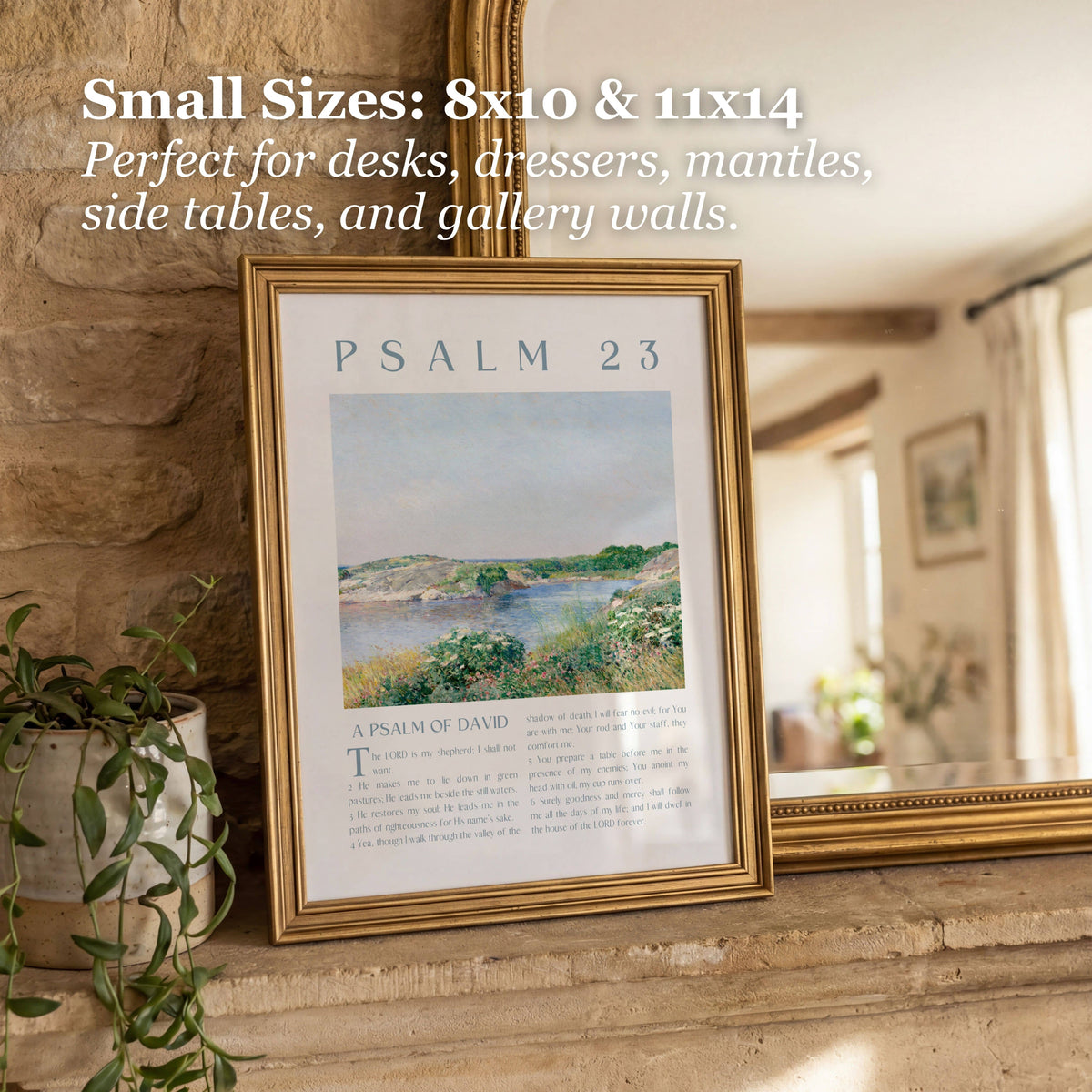 A framed wall art print leaning on a stone ledge in a home interior. The frame is gold-toned and contains a Psalm 23 print with a landscape illustration and text.