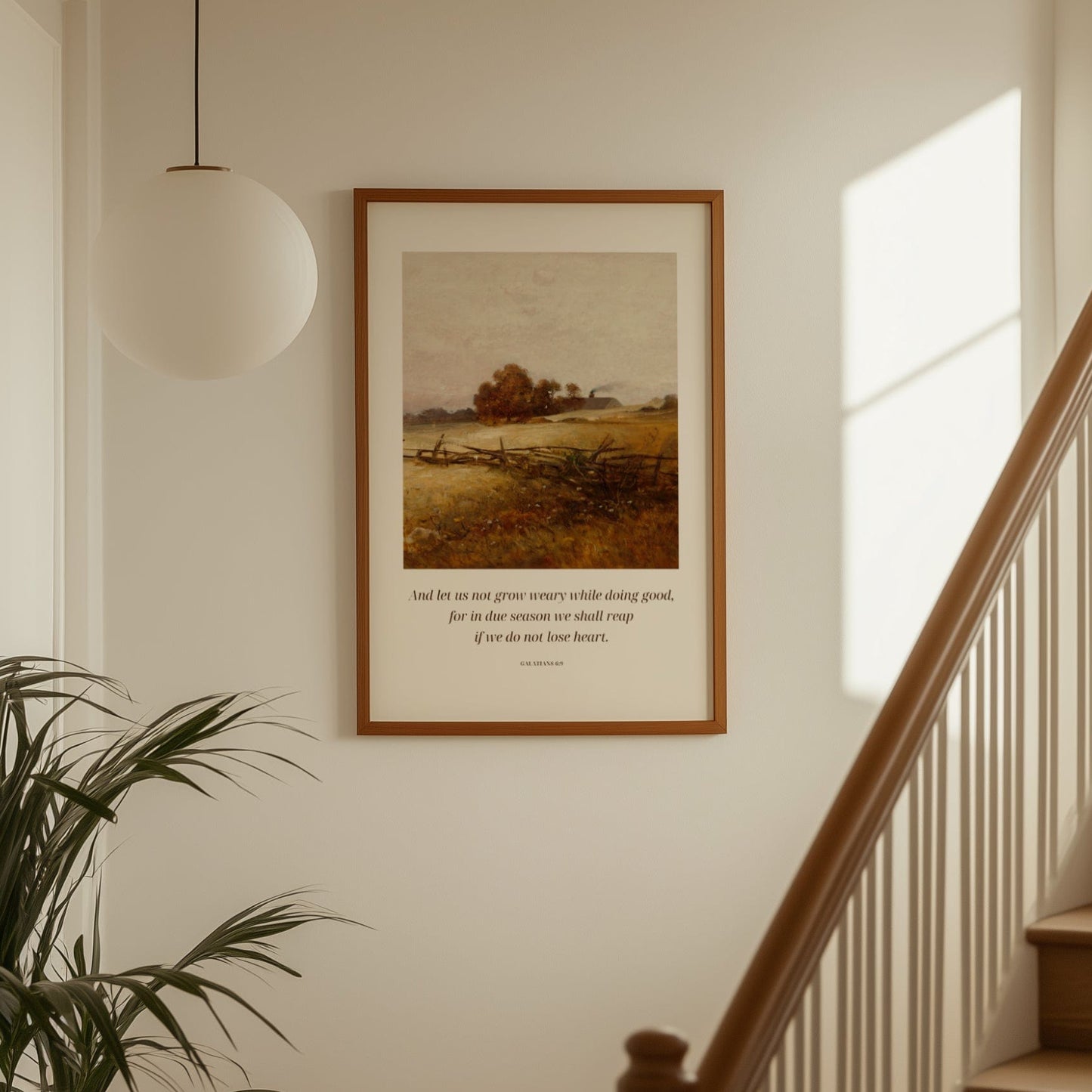 Framed artwork on a wall above a staircase with a plant to the left.
