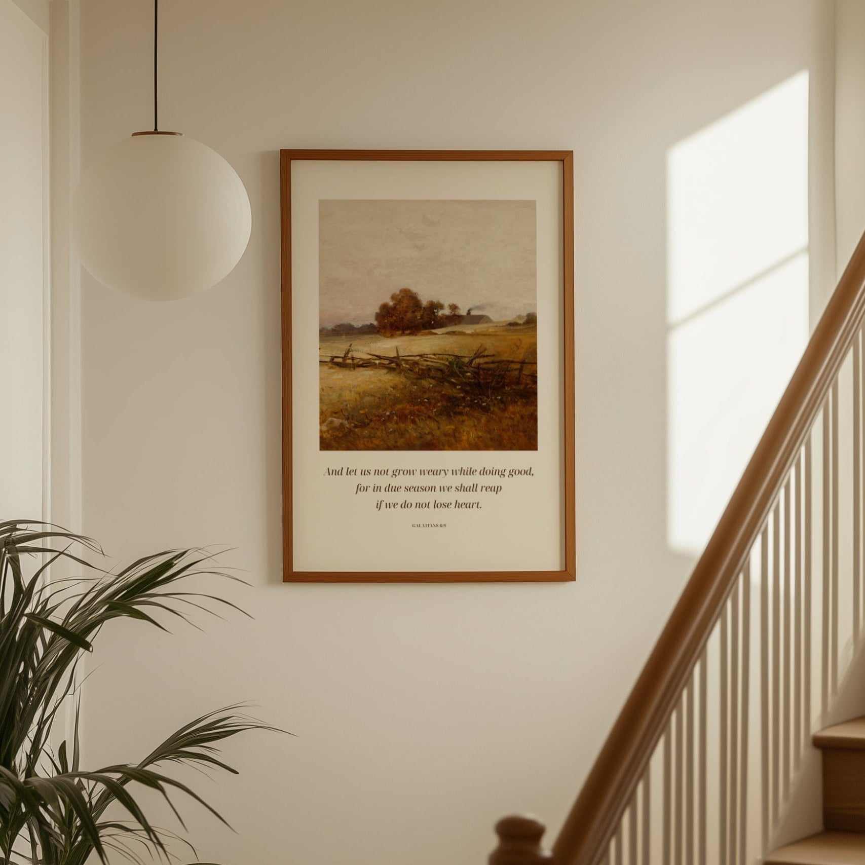 Framed artwork on a wall above a staircase with a plant to the left.