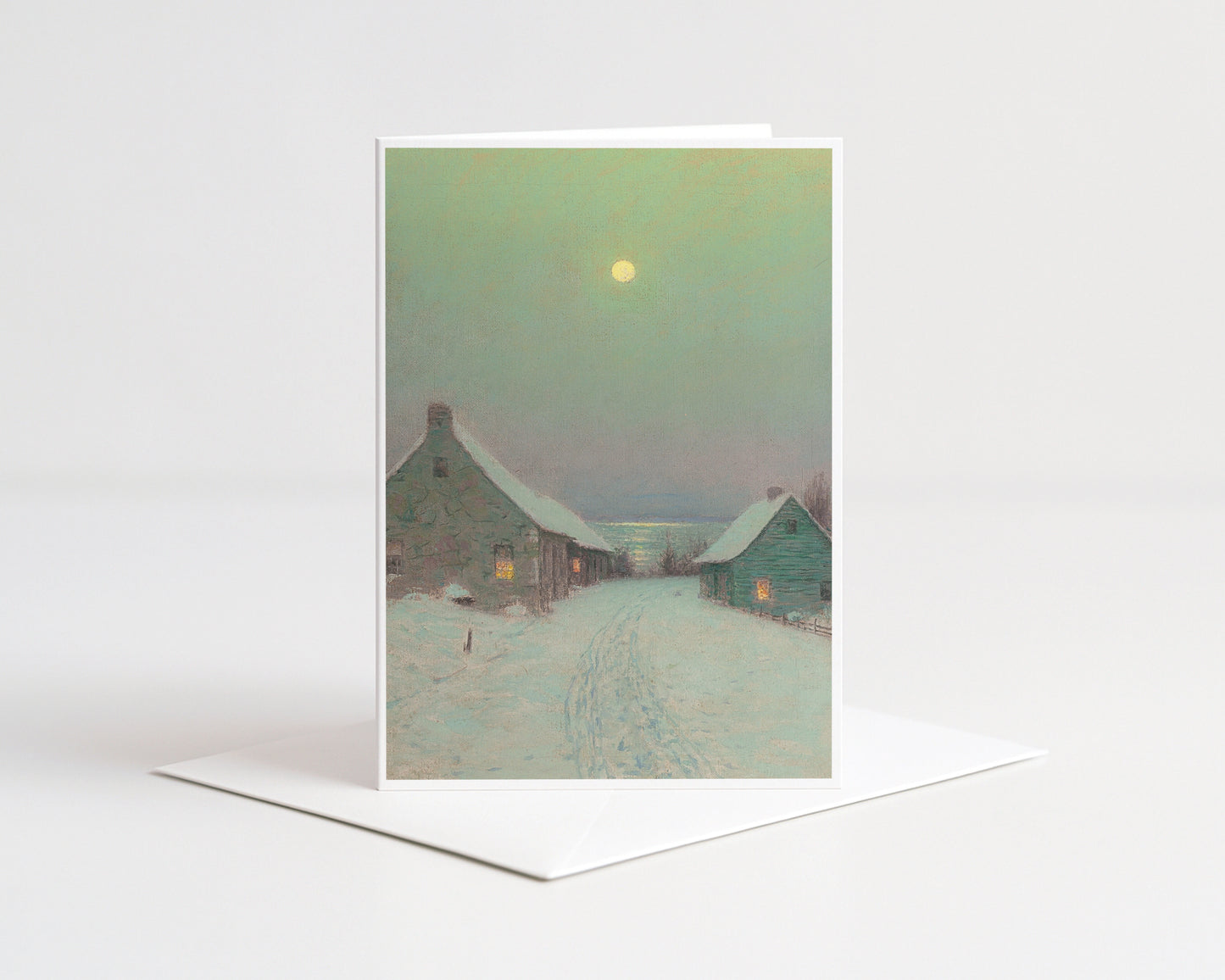Greeting card with a snowy village scene and moonlit sky on a white background