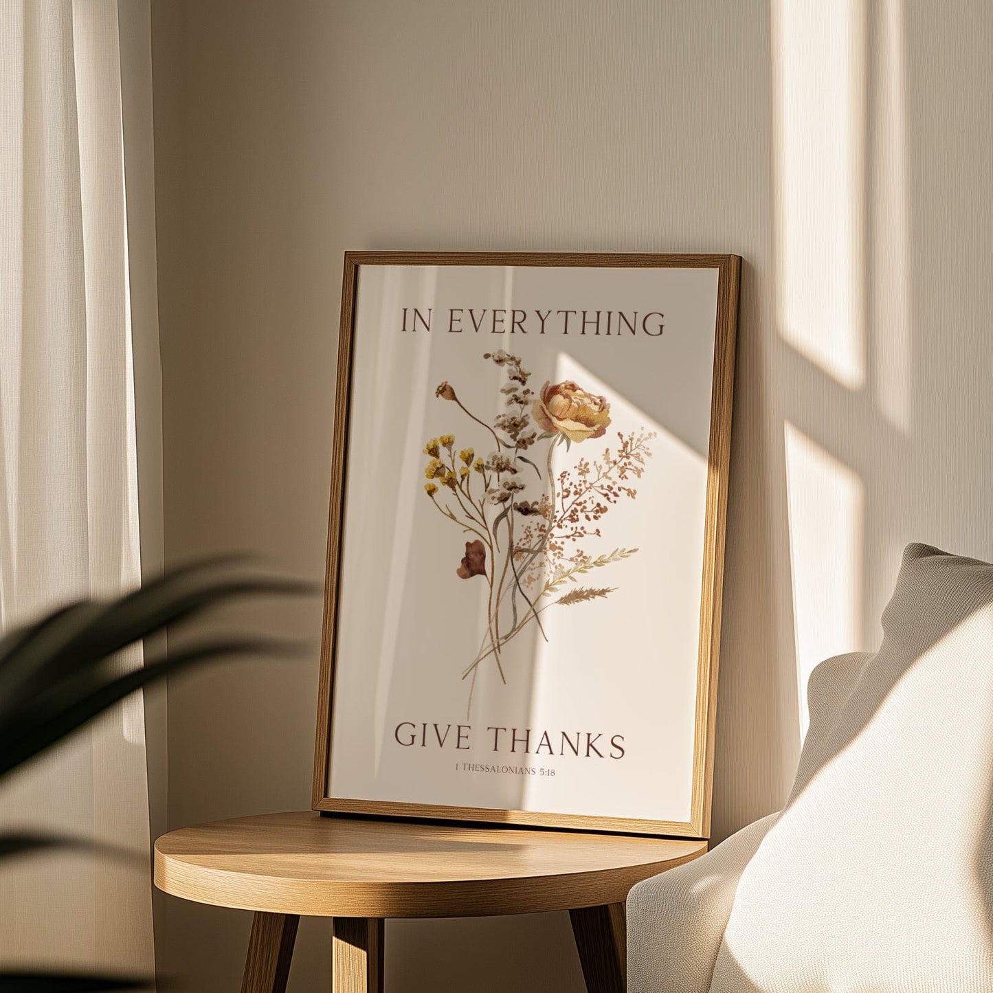Framed artwork with 'In Everything Give Thanks' text on a wooden side table in a softly lit room.
