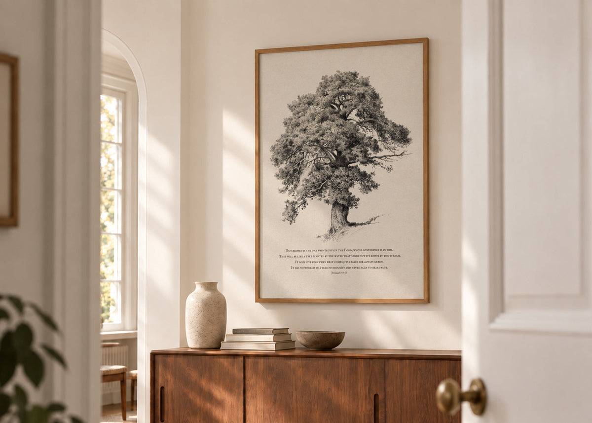 A framed black and white tree illustration with text hangs on a white wall above a mid-century modern wooden sideboard in a sunlit room.