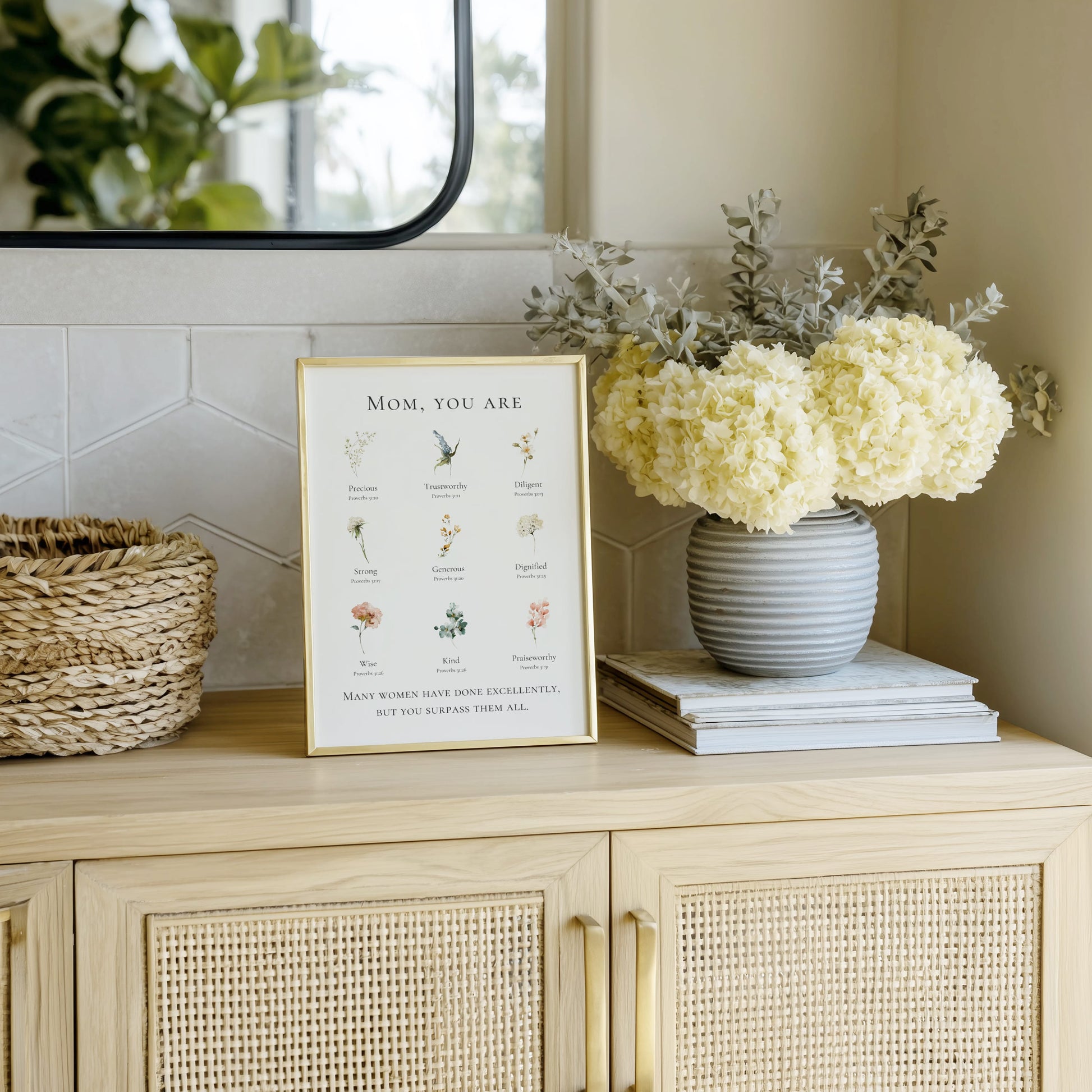 Decorative setup on a cabinet with a framed print, vase of flowers, and books.