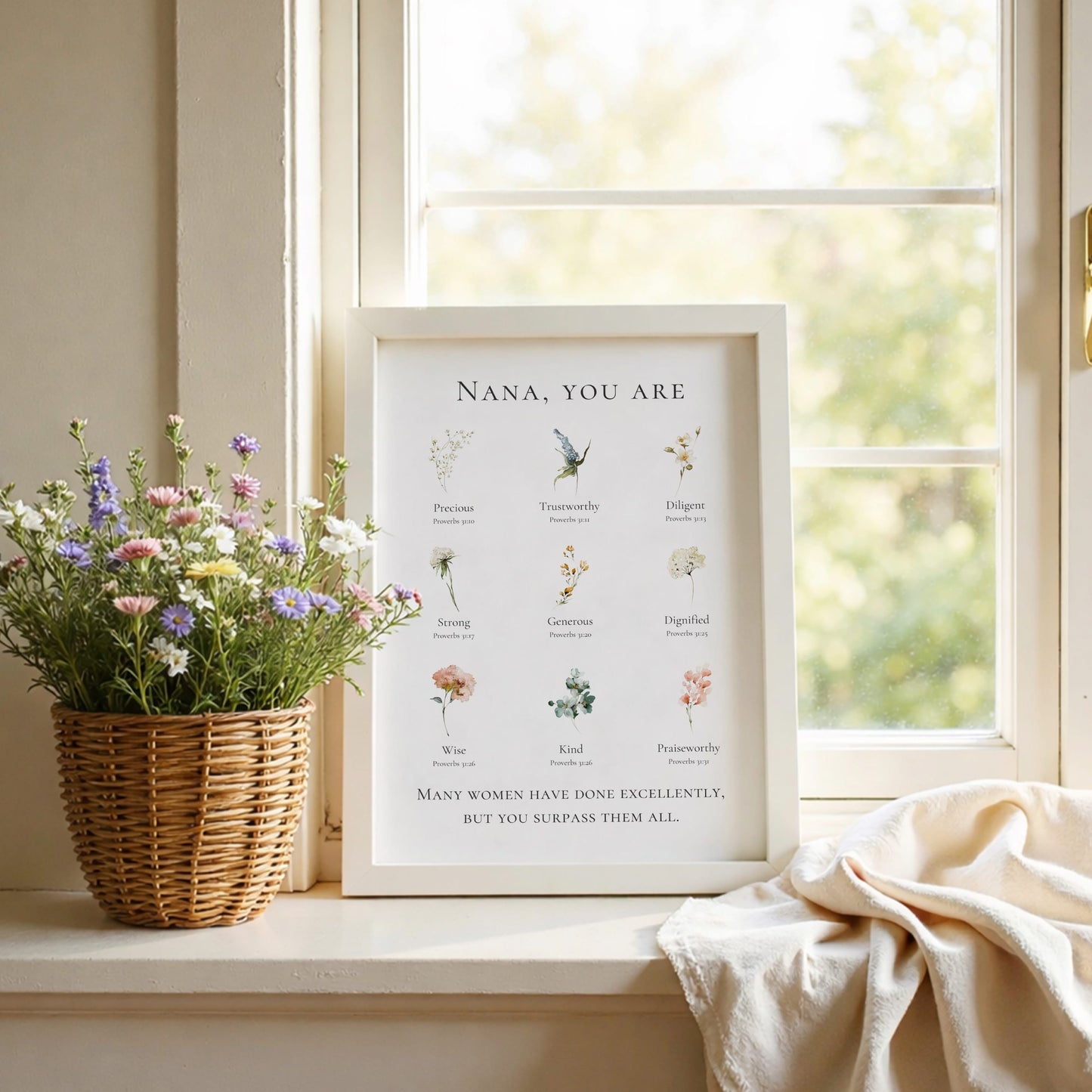 Framed print with floral illustrations and text on a windowsill with flowers and a blanket.