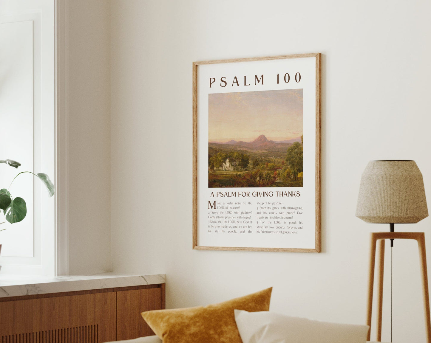 Living room with a framed poster of Psalm 100 on the wall, a plant on a windowsill, and a lamp.