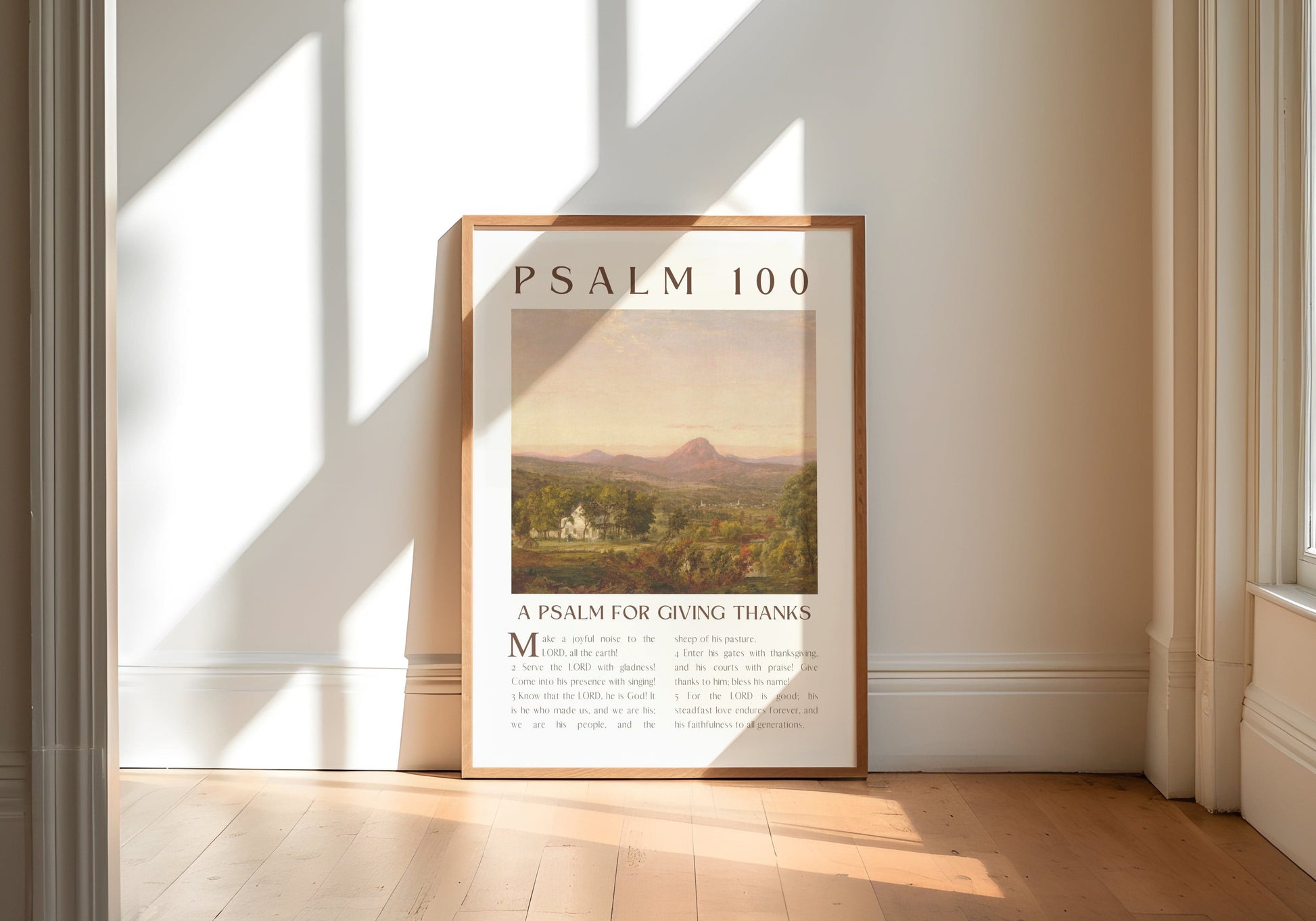 Framed poster titled 'Psalm 100' in a room with large windows and wooden floor.