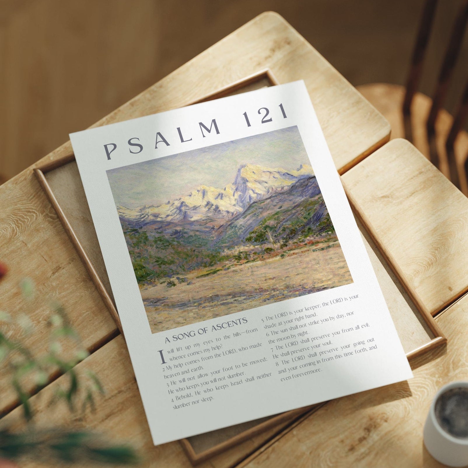 Sheet of paper with 'Psalm 121' text and illustration on a wooden table with a cup and plant.