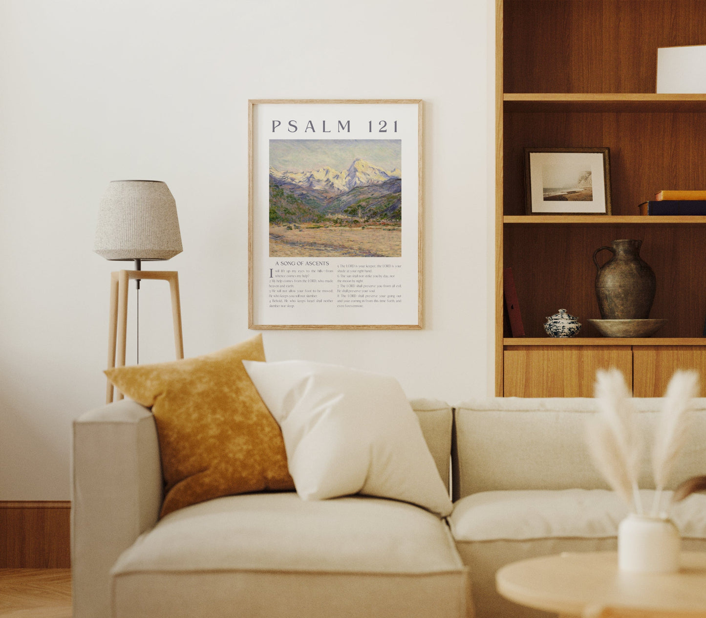 Living room with beige sofa, framed Psalm 121 artwork, and wooden bookshelf.