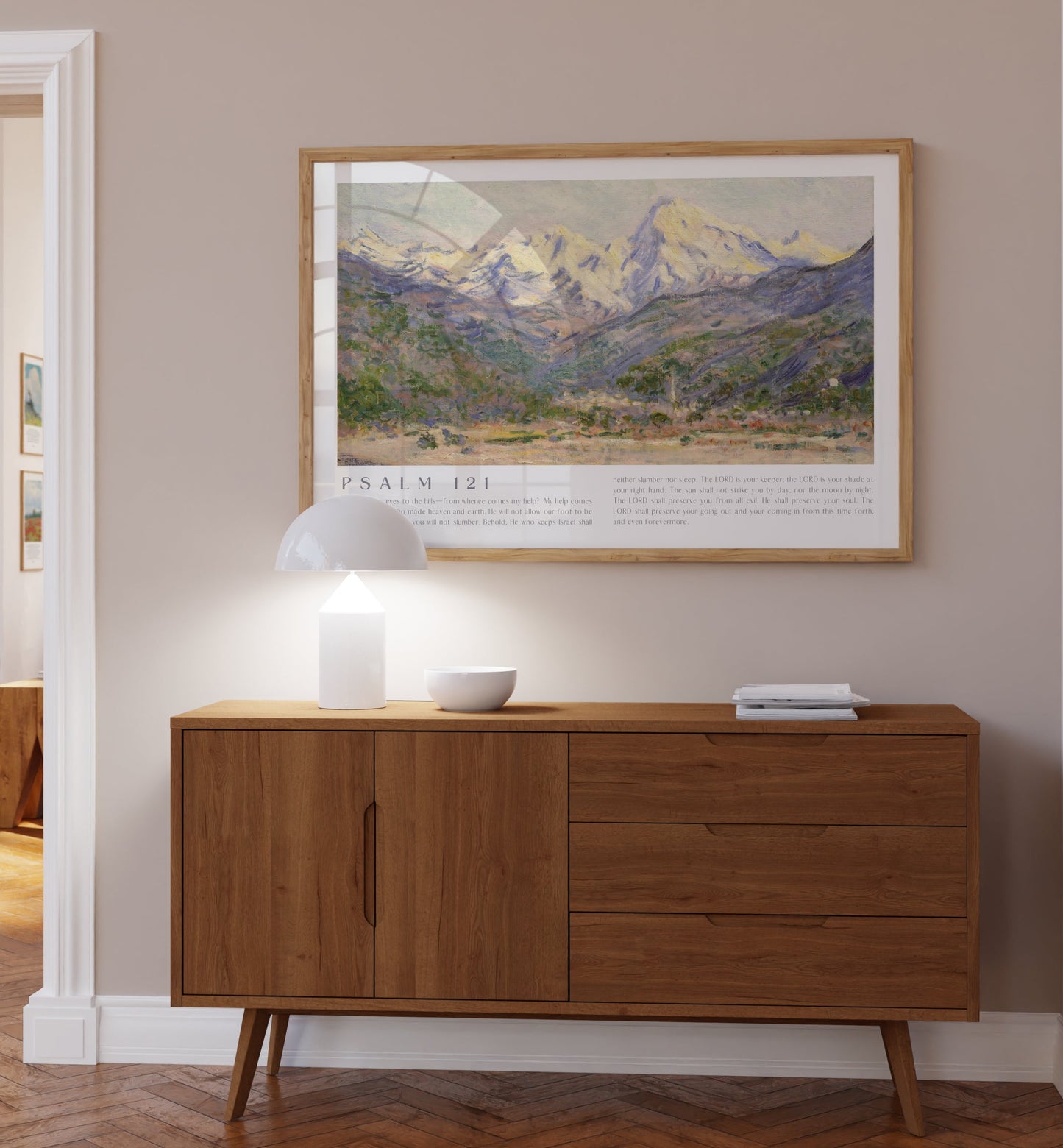 Wooden sideboard in a room with a framed landscape print on the wall.