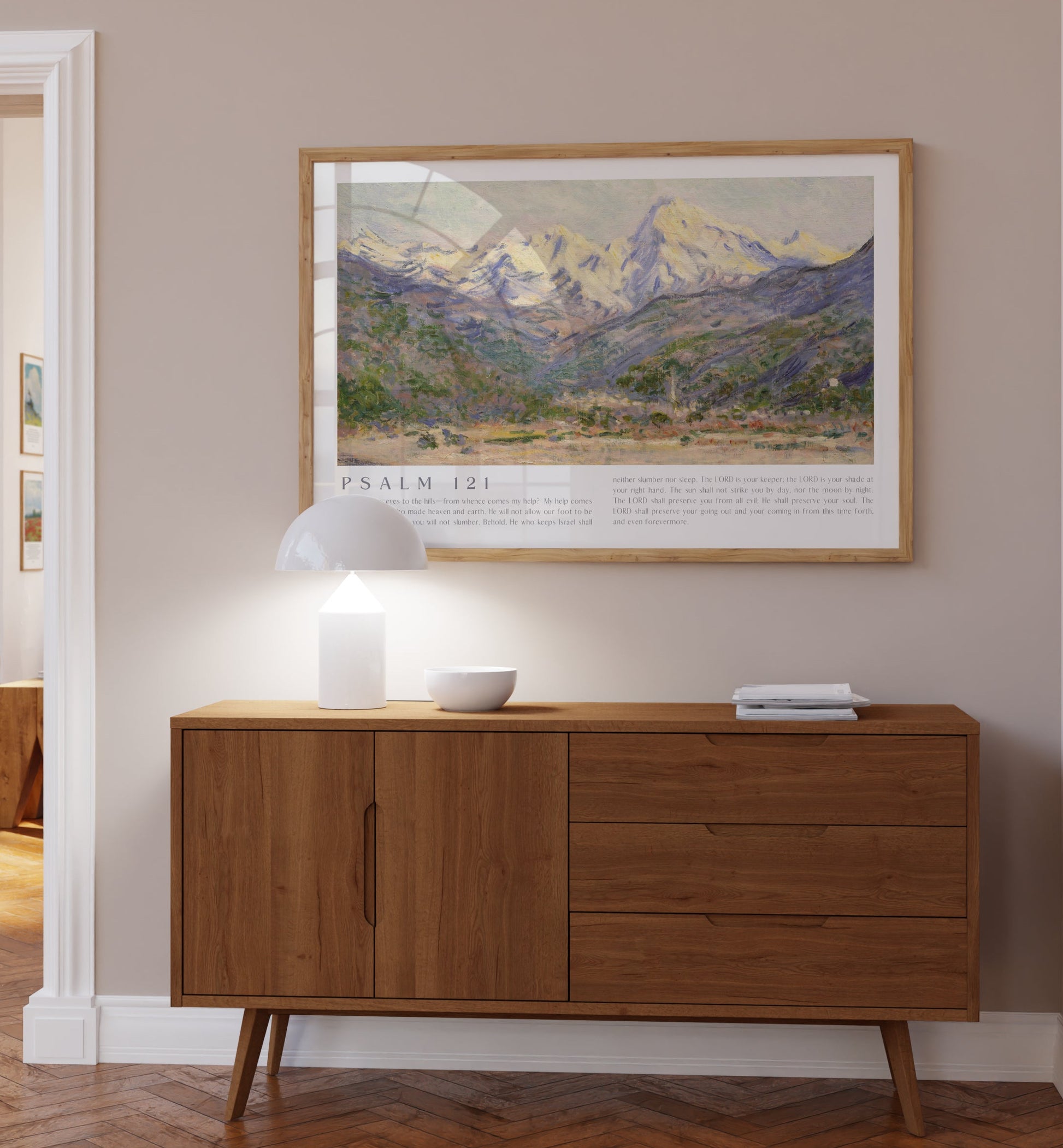 Wooden sideboard in a room with a framed landscape print on the wall.