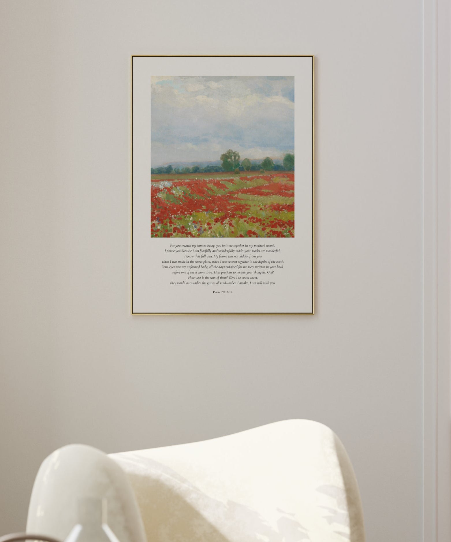 Framed artwork of a field with flowers on a wall in a room with a white chair.