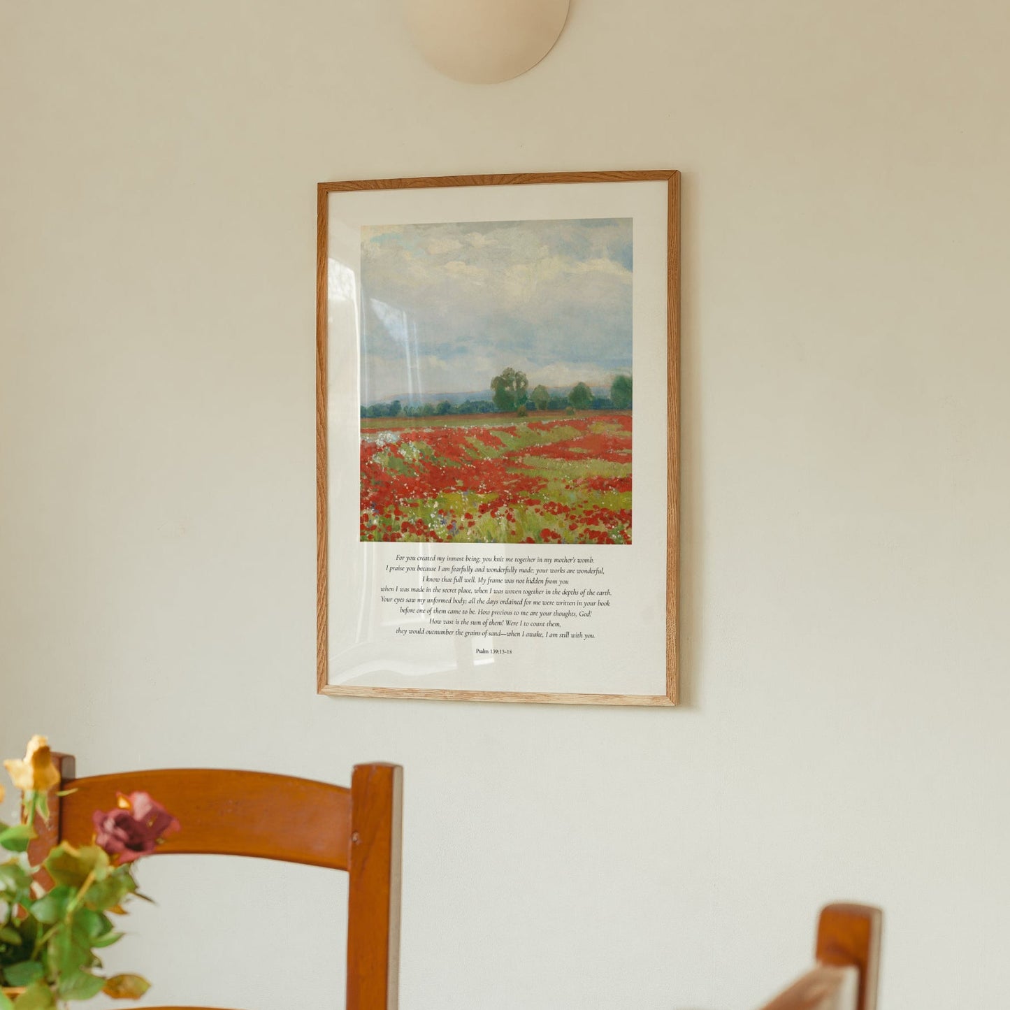 Framed artwork of a landscape with flowers and a chair in the foreground.