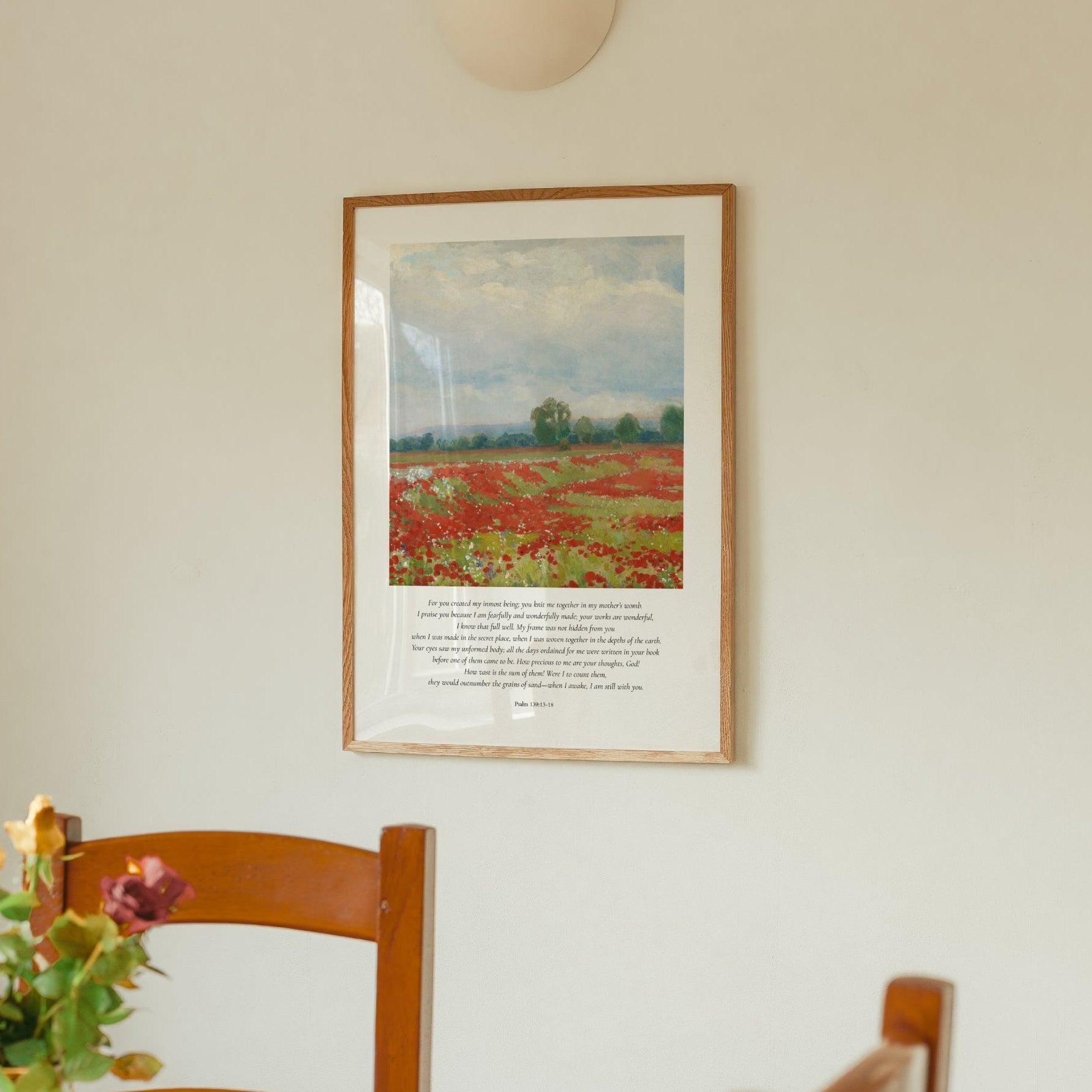 Framed artwork of a landscape with flowers and a chair in the foreground.
