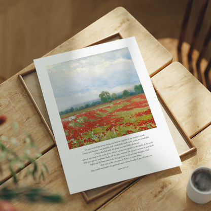 Art print of a field with red flowers on a wooden table with a cup and plant.