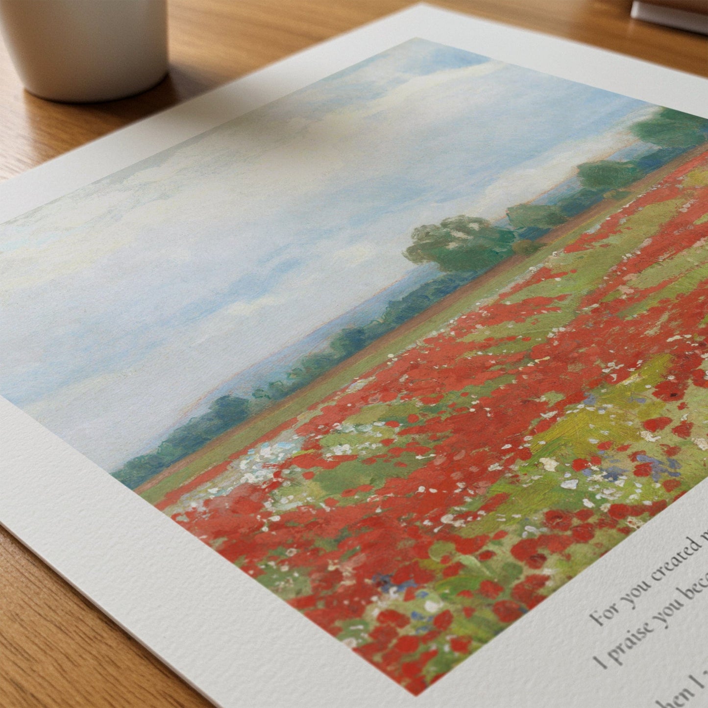 Printed artwork of a field with red flowers on a wooden surface