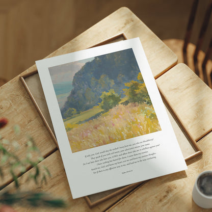 Framed artwork on a wooden table with a cup and plant in the background