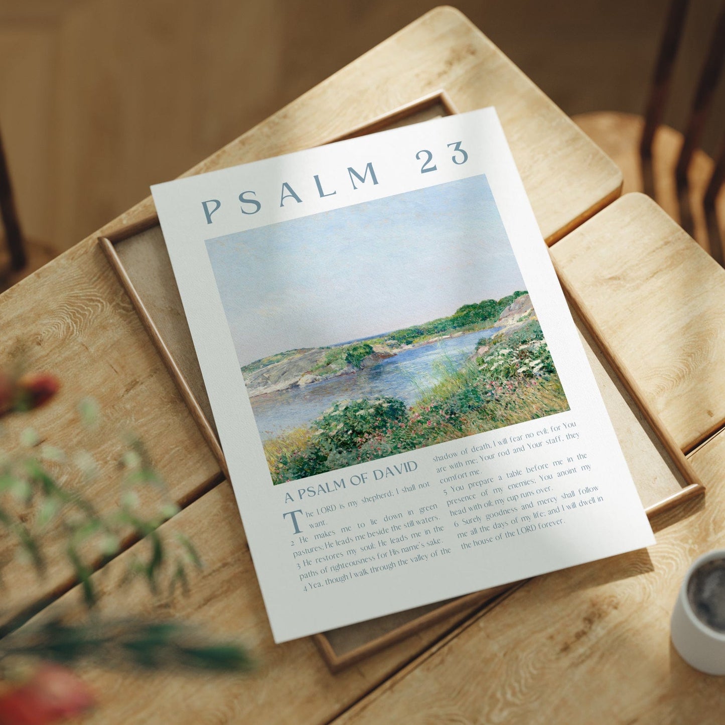 Poster titled 'Psalm 23' on a wooden table with a cup and plant.