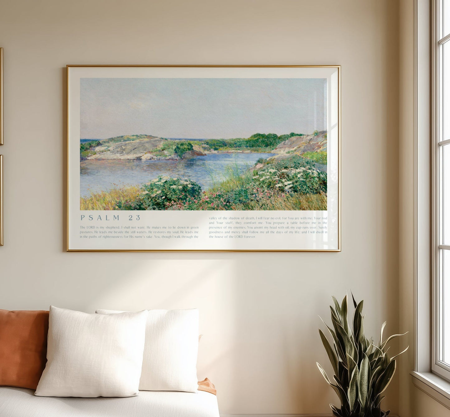 Framed landscape print on a wall above a sofa with decorative pillows and a plant.