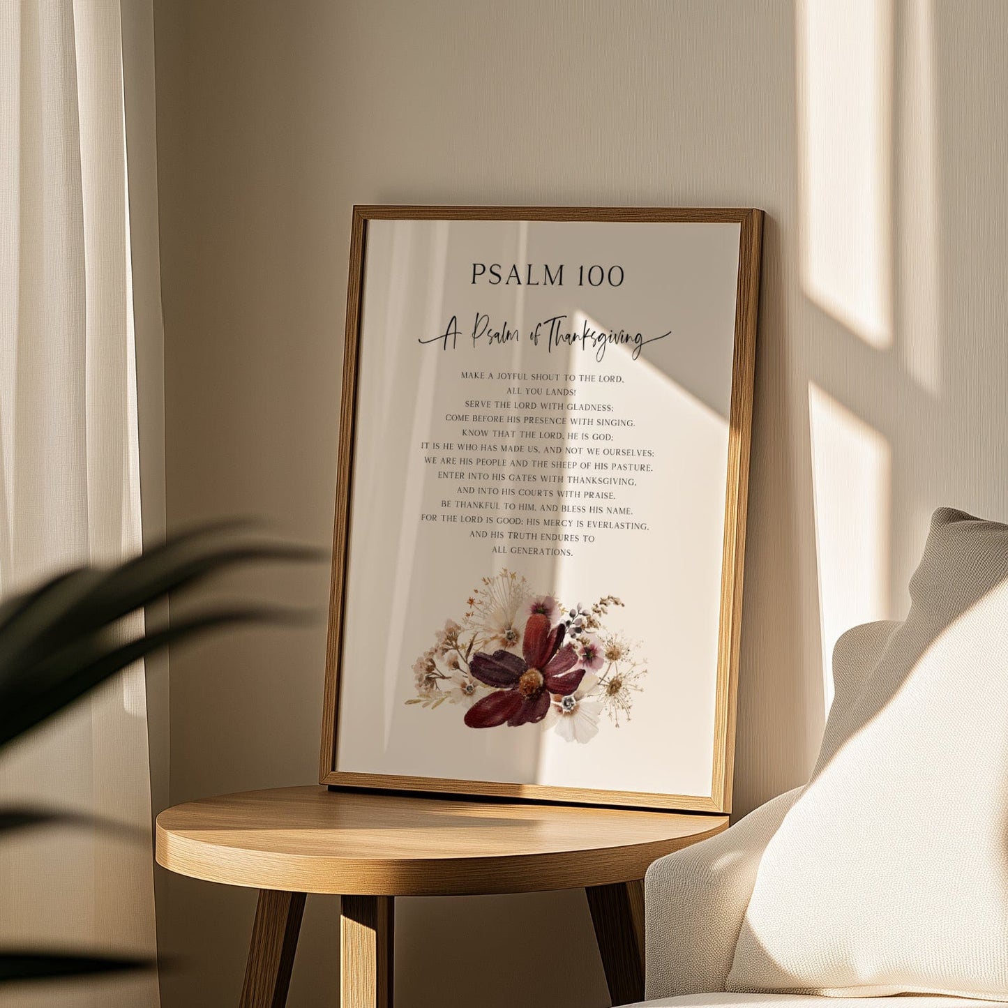 Framed artwork with text and floral design on a wooden side table in a room with a couch and curtains.