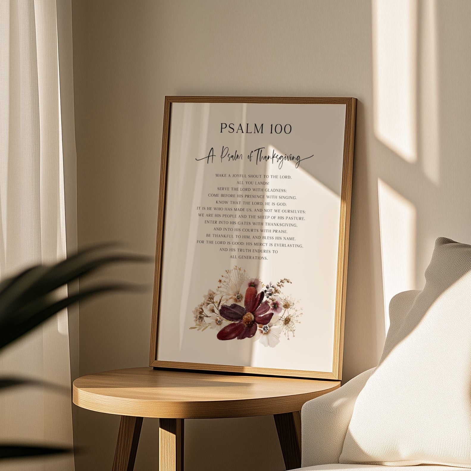 Framed artwork with text and floral design on a wooden side table in a room with a couch and curtains.