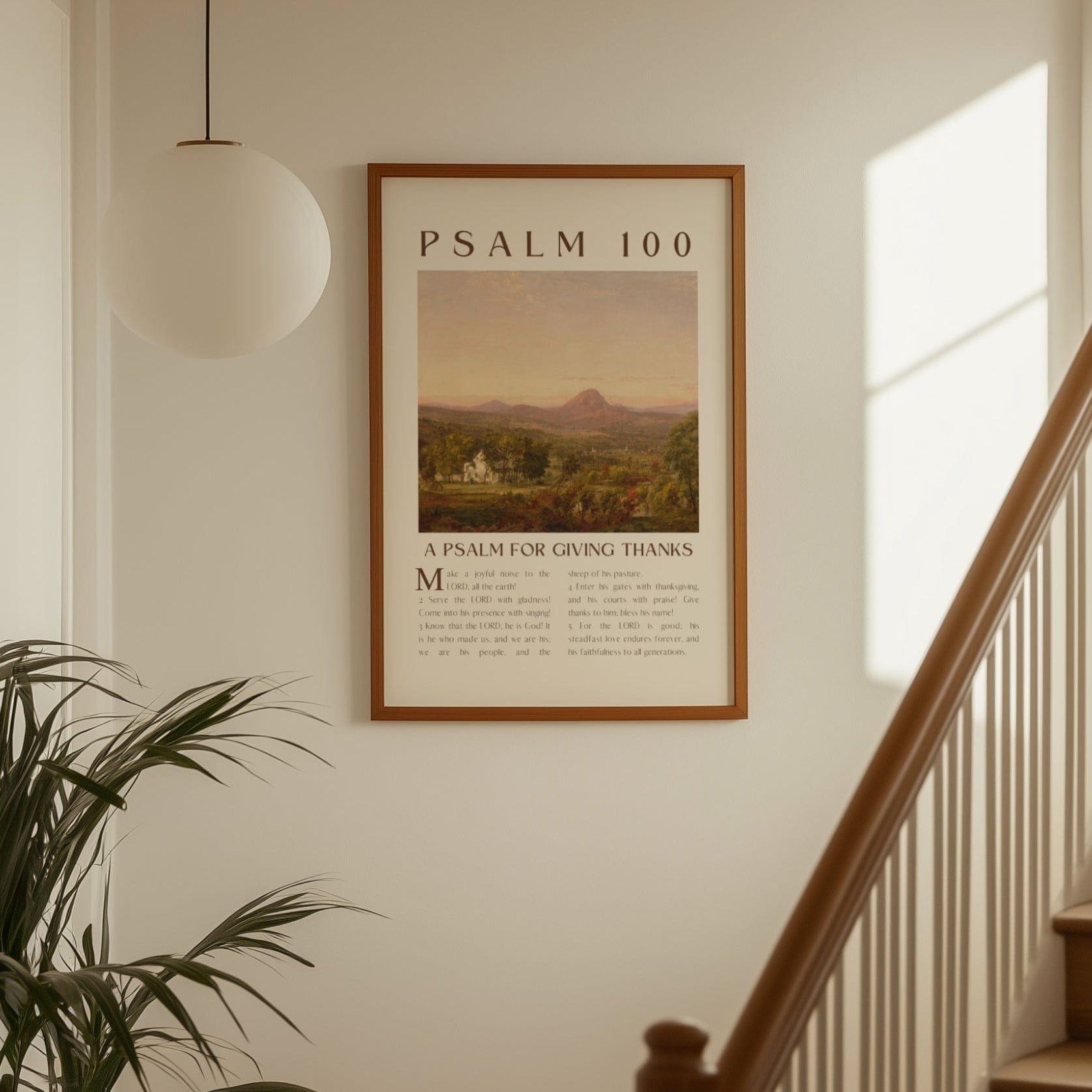 Framed poster of Psalm 100 on a wall above a staircase with a plant to the left.