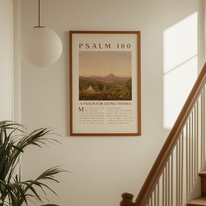 Framed poster of Psalm 100 on a wall above a staircase with a plant to the left.