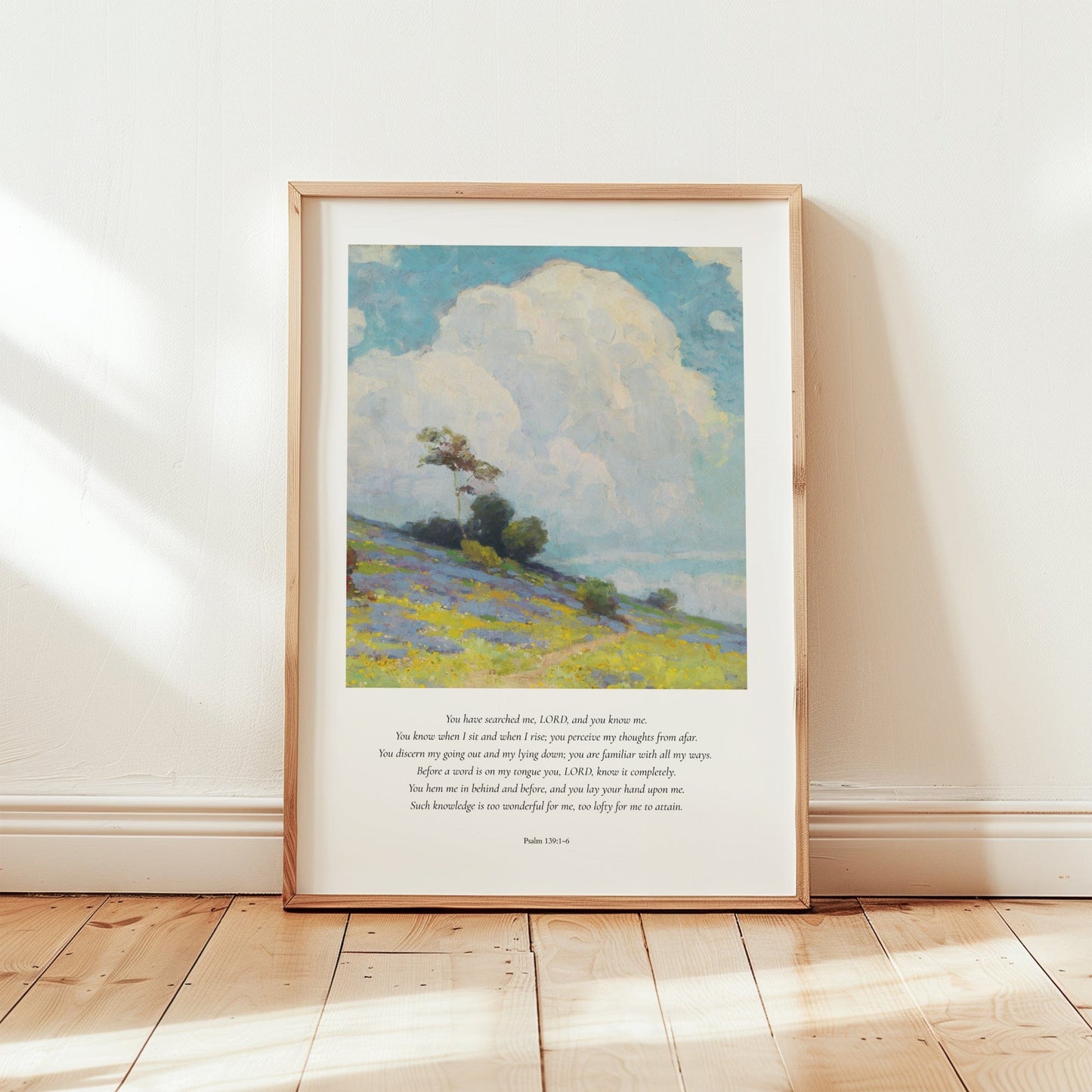 Framed artwork of a landscape with a blue sky and green field on a wooden floor.