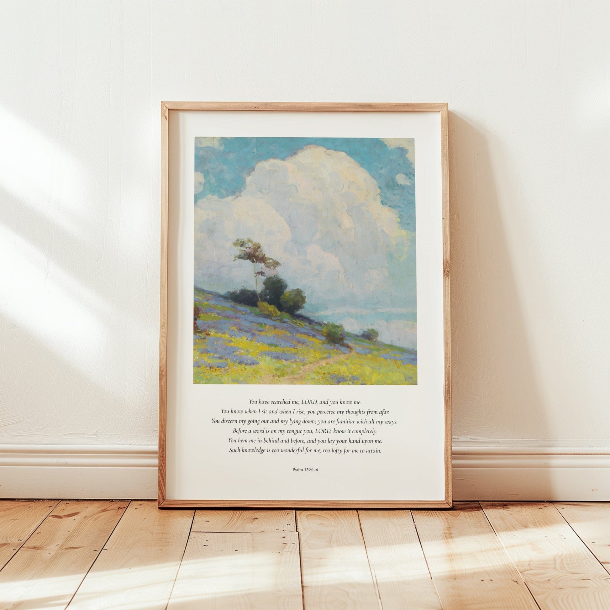 Framed artwork of a landscape with a blue sky and green field on a wooden floor.