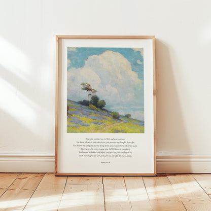 Framed artwork of a landscape with a blue sky and green field on a wooden floor.
