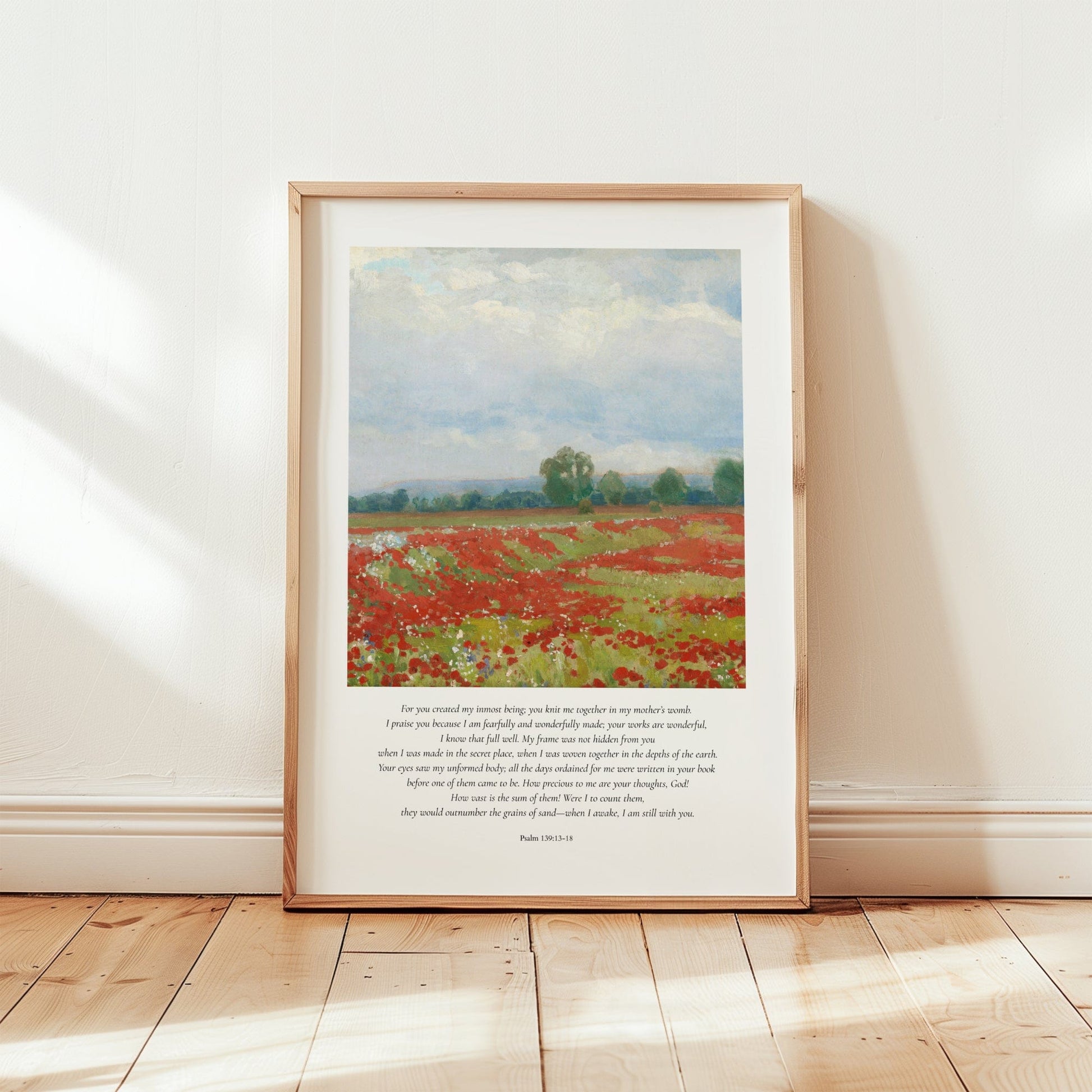 Framed artwork of a field with red flowers on a white wall.
