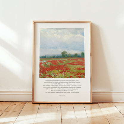 Framed artwork of a field with red flowers on a white wall.