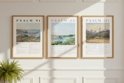 Three framed prints of Psalm 91, Psalm 23, and Psalm 121 on a wall with a plant on a table.