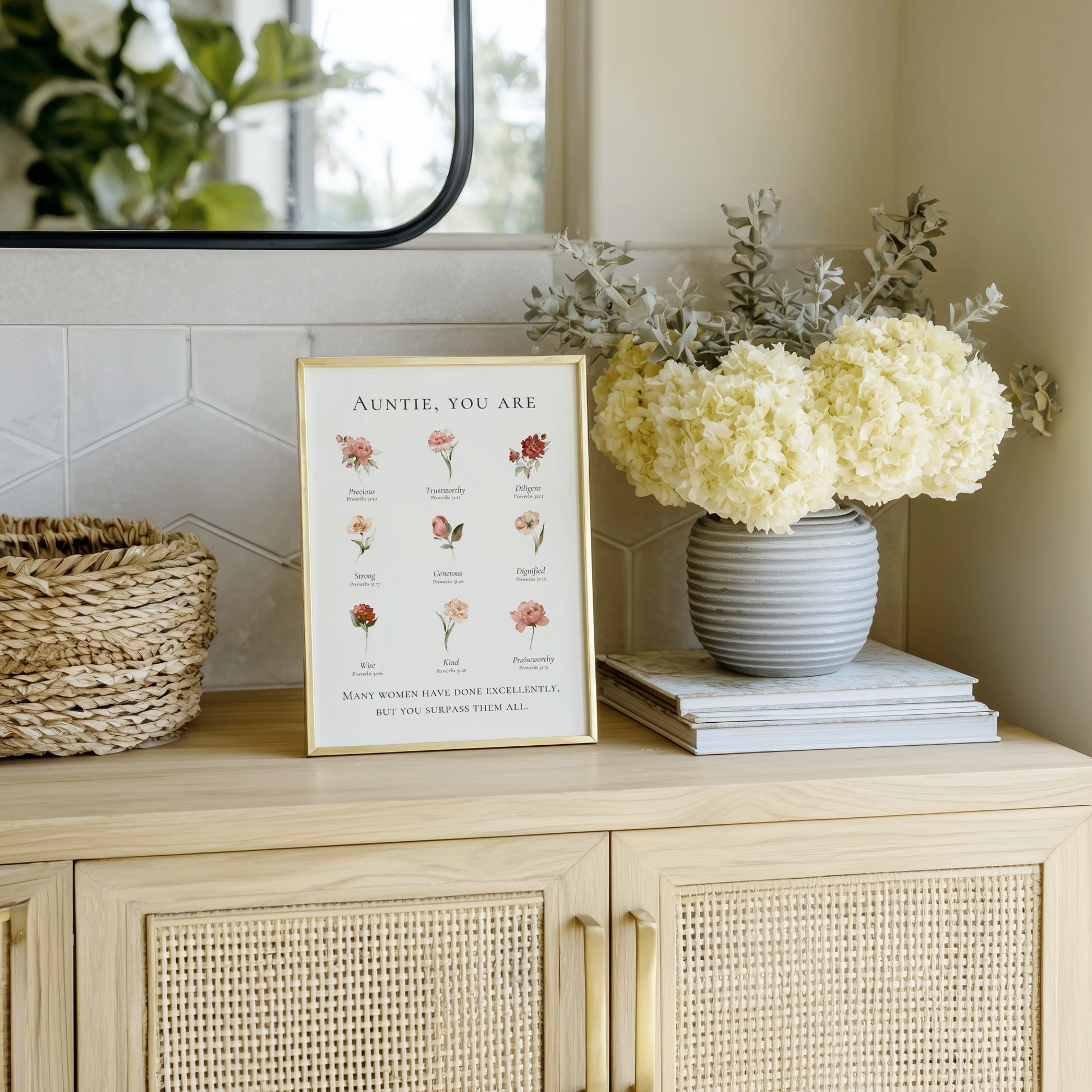Decorative setup on a cabinet with a framed print, flowers, and books.