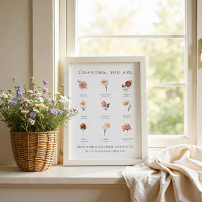 Framed print with floral illustrations and text on a windowsill with flowers and fabric.