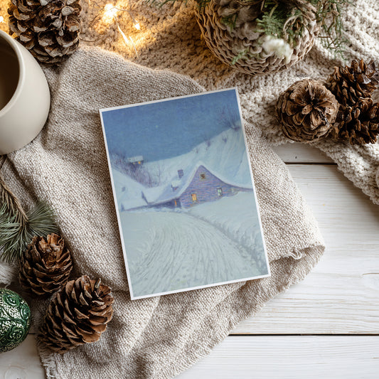Winter-themed card with a snowy landscape and house, surrounded by pine cones and a mug on a textured surface.
