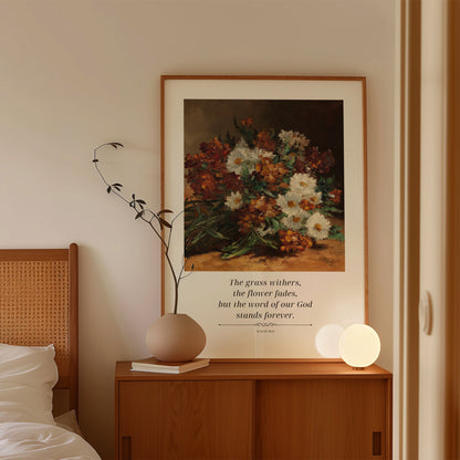 Framed floral artwork on a wooden nightstand with a quote, next to a bed.